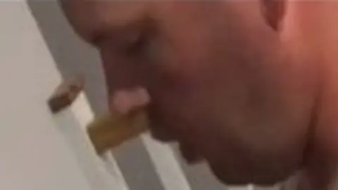 Wiltshire Police A very close up side profile of a large, white man's face. He is in front of a stair banister.