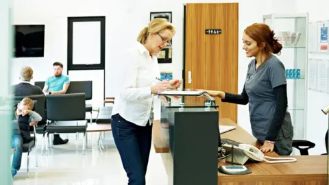 Getty Images Patient fills out a form in a GP surgery