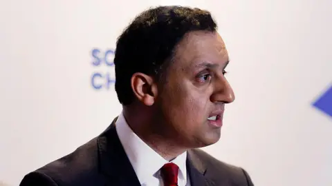 Getty Images Anas Sarwar looks ahead with a serious expression on his face. He has short dark hair and wears a white shirt, red tie and black suit.