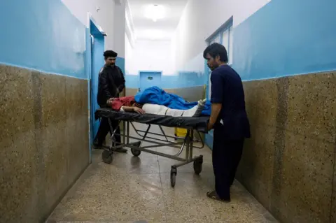 Getty Images Afghan volunteer and medical staff member carry an injured man on a stretcher at Wazir Akbar Khan hospital