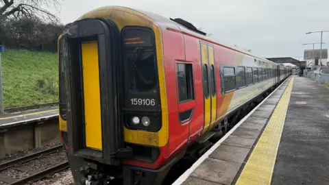 A old looking train on an unidentifiable train platform.