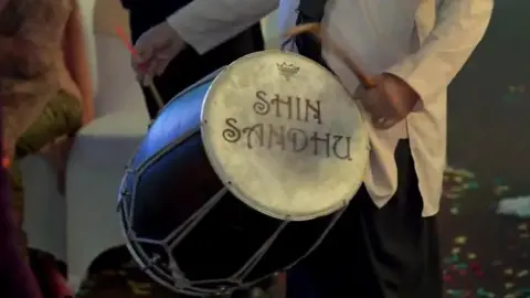 Supplied Surinder Sandhu playing his dhol, which has his name written on the side.