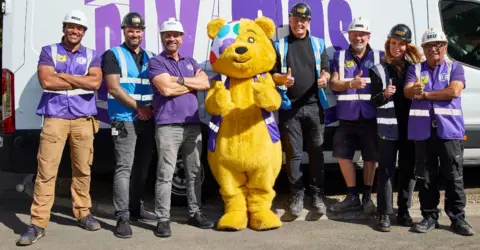 Pudsey and the DIY SOS team, standing in front of a van