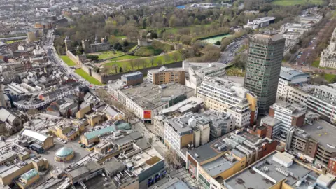 A drone image of Cardiff from above. It shows Queen St and Castle St, with Cardiff castle and Bute park in the background. 