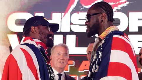 Derek Chisora and Deontay Wilder face off at a news conference draped in the flags of their country