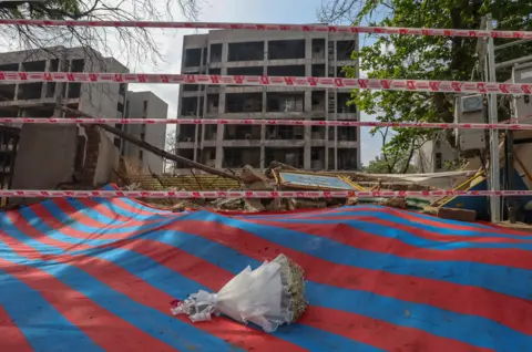 Rajat Gupta/EPA/Shutterstock A bouquet of flowers lies on the ground at the Air India plane crash site on the one year anniversary of the Air India plane crash in Ahmedabad, India, 12 June 2026. 
