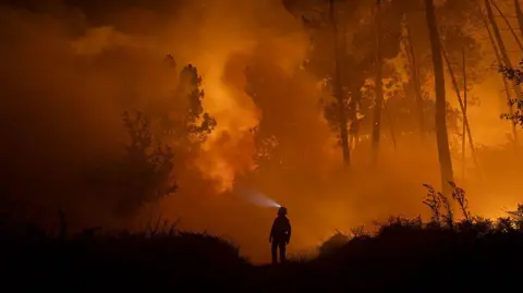 Getty Images A member of the Emergency Military Unit (UME) works to extinguish a wildfire next to a village on 19 August 2025 in Pepín, in Ourense province, Spain.