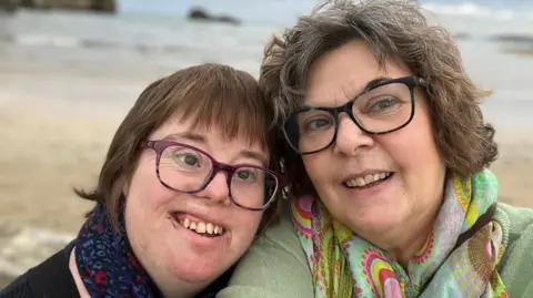 Carol Beardmore A mother and daughter taking a selfie on a beach smiling.