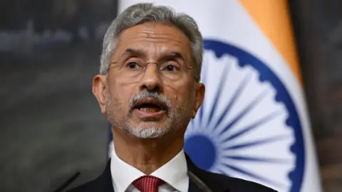 Reuters India's Foreign Minister Subrahmanyam Jaishankar attends a joint press conference with Russia's Foreign Minister Sergei Lavrov following their talks in Moscow, Russia December 27, 2023. He is wearing glasses and a white shirt with a red tie, and is standing in front of an Indian flag.