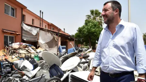 Getty Images Matteo Salvini stands by a pile of rubbish as he tours the Mineo migrant centre, 9 July 2019