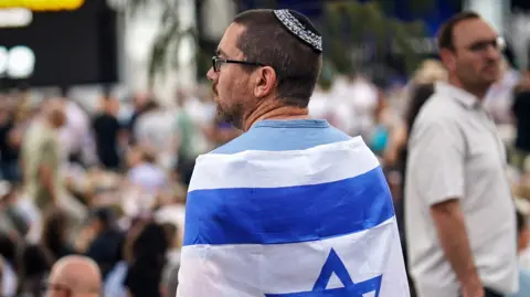 A man wearing a kippah draped in an Israeli flag