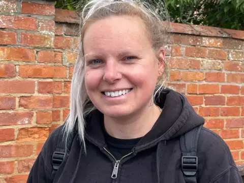 Marie Taylor. She has blonde hair and is wearing a black hoodie.