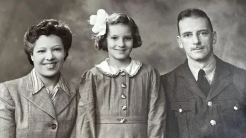 Ann Mathers A black and white picture of Ann Mathers with parents Nena and Arthur "Jay" Jenkins taken in the 1940s.
