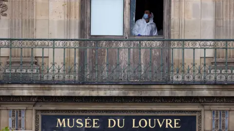Reuters A police forensic expert looks out of a broken window at the Louvre museum in Paris. It is an upper floor window with a balcony and a sign saying Museé Du Louvre underneath