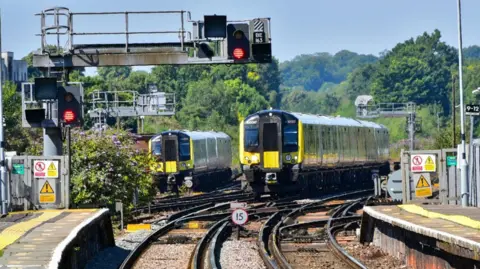 Two South Western Railway trains approach a station.