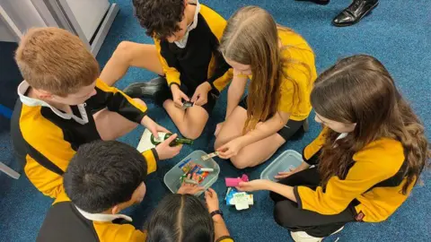 Hope UK A group of children sit in a circle with their heads bowed so they can't be identified. They hold sweets and pills.