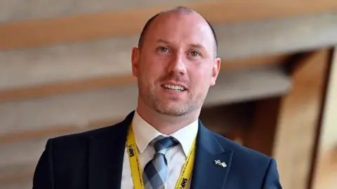 Getty Images A man in a suit with a bald head wearing a yellow lanyard and scotland ukraine pin badge