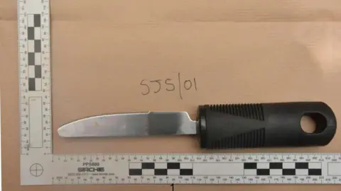 Crown Prosecution Service A butter knife with a black handle placed on a piece of brown material