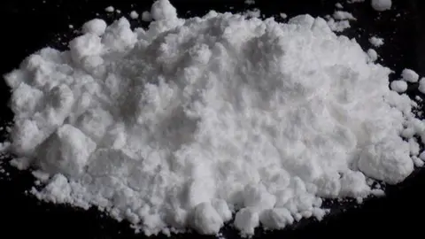 A white powder in a pile on a black surface. 