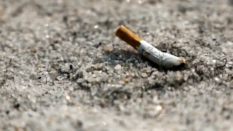 A discarded cigarette butt on some sand.