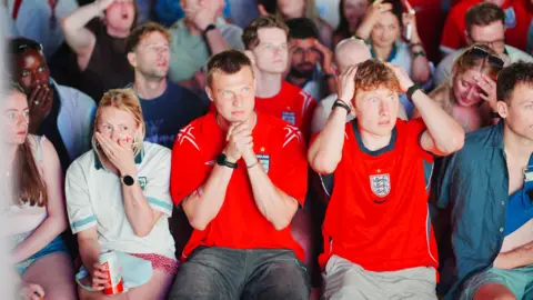 PA Media England fans sit in shock, some with heads in hands and others with hands over their mouths.