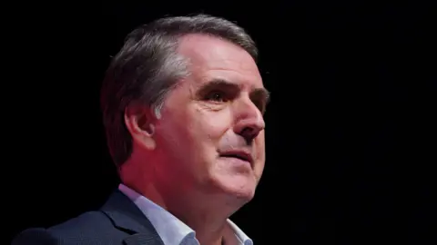 Steve Rotheram delivering a speech on stage at a conference