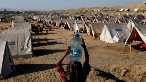 Reuters Girl carries water bottle into camp for people displaced by Pakistan flooding