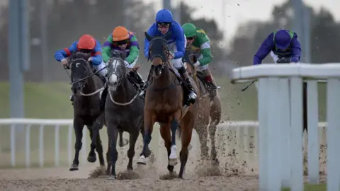 PA Media Jockeys wearing colourful racing silks riding their horses along the track in Chelmsford.