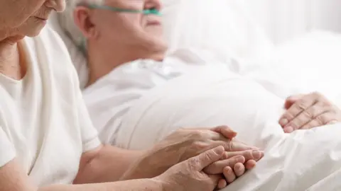 Getty Images Holding hands of a dying man