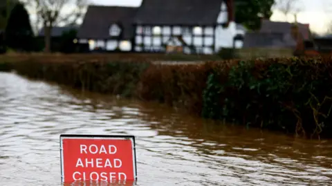 Reuters A sign is partially submerged as the village of Severn Stoke is cut off amid flooding after heavy rain from Storm Henk