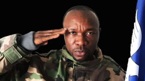 Lucas Ayaba Cho in military uniform, saluting