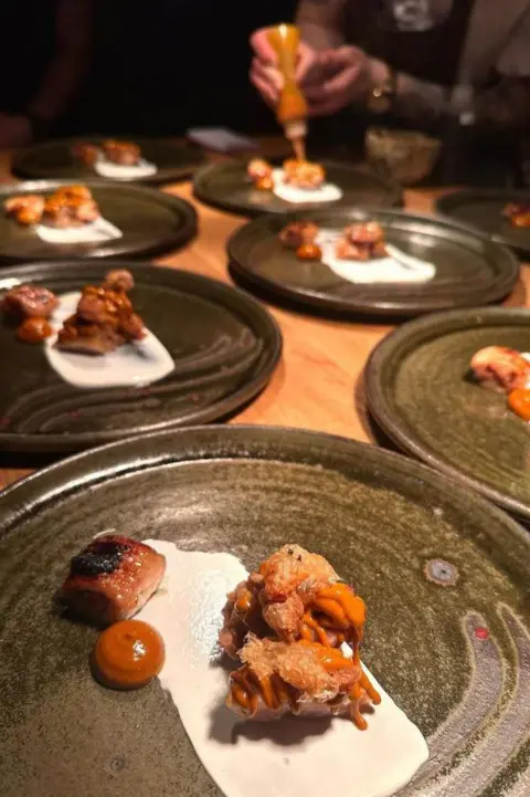 Instagram/Gwen restaurant Plates of food being served - the plate is green and it has a white sauce on it alongside three other bits of food.