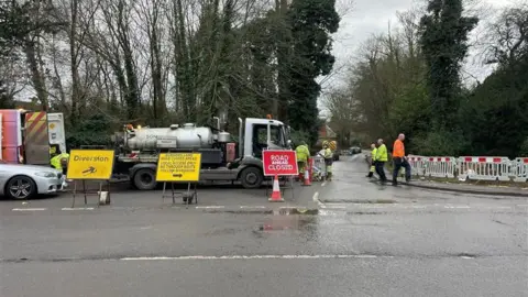 Clare Cowan/BBC A road closed sign with a SGN tanker and fences blocking the road