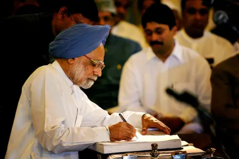 Getty Images Singh menandatangani surat resmi setelah mengambil sumpah jabatan di Delhi pada 22 Mei 2004. 