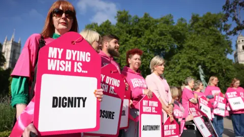 EPA Campaigners in favour of assisted dying outside Parliament, wearing pink and holding placards reading: "My dying wish is... dignity".