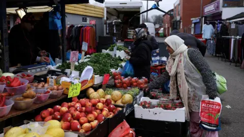 Reuters A woman with a headscarf leans over to pick up some fruit from an outdoor seller in Gorton. 