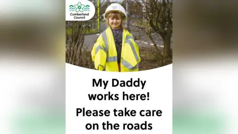 Cumberland Council A little girl wears over-sized hi-vis and a helmet. Underneath are the words: My daddy works here! Please take care on the roads.