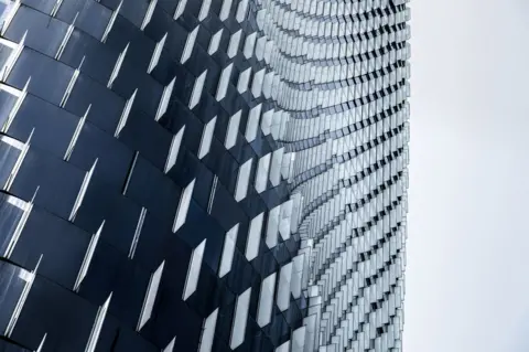He Zhenuan / APA18 A curved building exterior wall with glass and metal panels