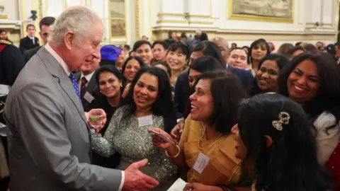 Reuters Britain's King Charles speaks with guests as he meets nurses and midwives to celebrate their work, at Buckingham Palace, in London