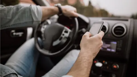 Getty Images Someone driving while using the phone