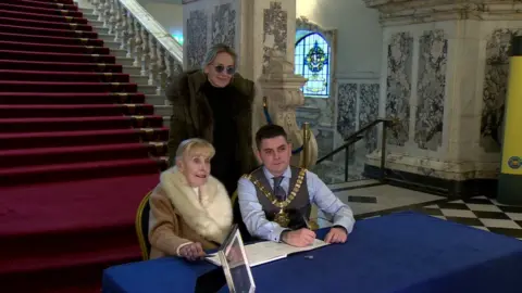 BBC Sharon Stone, Betty Williams and Belfast Lord Mayor Daniel Baker signed the book of condolence