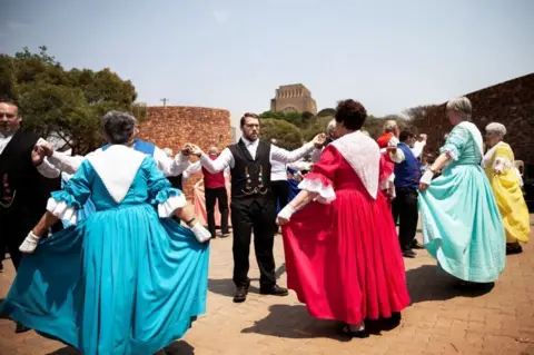 AFP People dressed in traditional Volkspele (a traditional Afrikaner dance) attire, dance at the Voortrekker Monument in Pretoria on Heritage Day on September 24, 2018. - People of Afrikaner descent gathered at the Voortrekker Monument in Pretoria on September 24, 2018 to celebrate Heritage day.