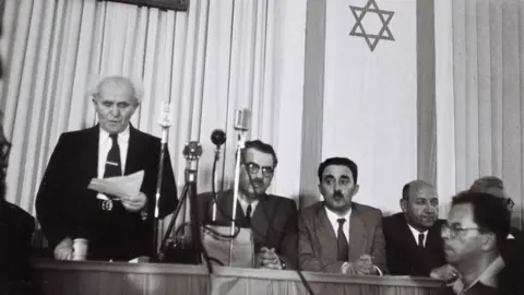 GPO via Getty Images David Ben-Gurion (left) reads the Israeli Declaration of Independence on 14 May 1948