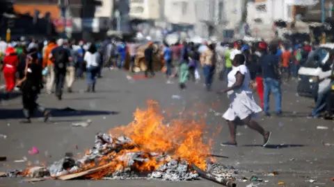 Reuters Locals run as supporters of the opposition Movement for Democratic Change (MDC) party of Nelson Chamisa burn barricades in Harare, Zimbabwe, 1 August 2018