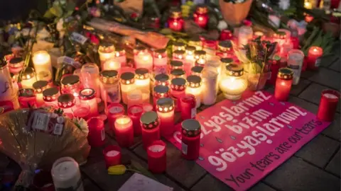 Getty Images Candles, flowers and a sign with the slogan "Your tears are our tears" pictured near the scene of one of the shootings in Hanau, Germany