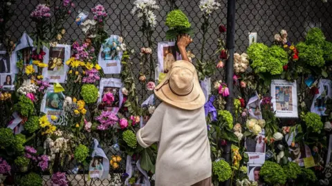 Getty Images A woman adds flowers to a memorial outside Champlain Tower