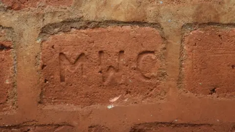 Brick with initials MWC on it