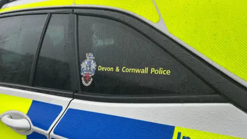 A close up of the side of a yellow and blue Devon and Cornwall Police car.