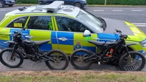 Merseyside Police Police car pictured next to two bikes 