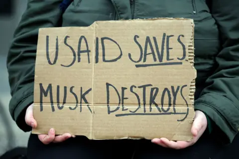 Getty image sign says that USAID Save, musk is destroyed